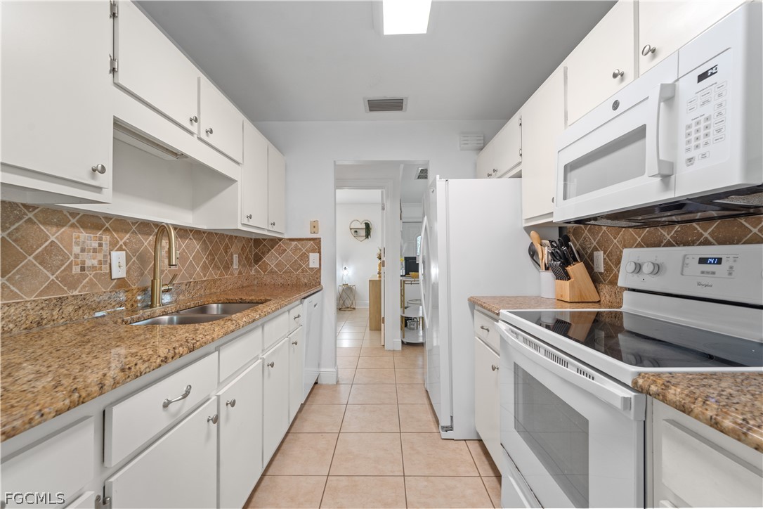 939 Bluebird Street Naples, FL 34104 - Photo 7 of 29 a kitchen with granite countertop cabinets a sink and a stove