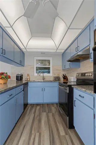 a kitchen with granite countertop white cabinets and stainless steel appliances