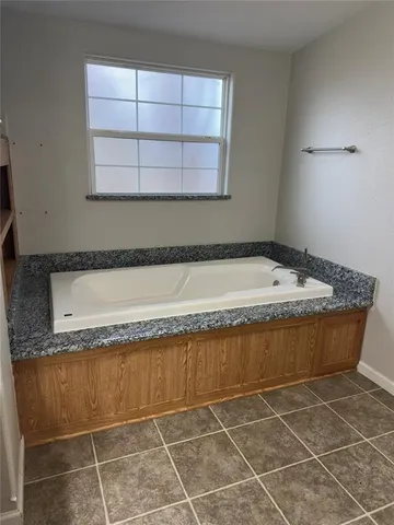 a bathroom with a granite countertop bathtub and window