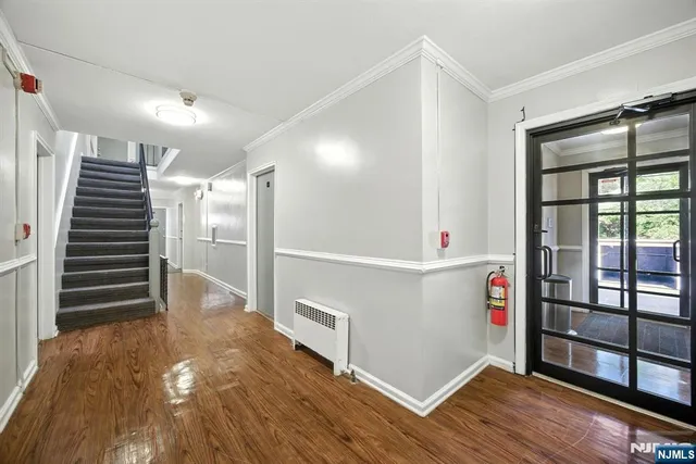 a view of an empty room with wooden floor and windows