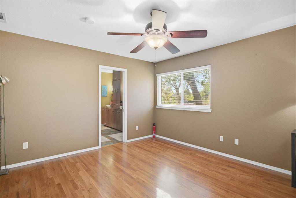1004 Usher Street Benbrook, TX 76126 - Photo 14 of 25 a view of an empty room with wooden floor and a ceiling fan