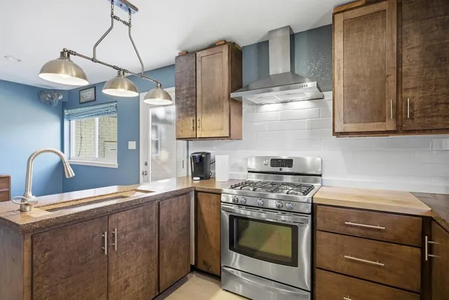 a kitchen with stainless steel appliances granite countertop a sink a stove and a wooden floors