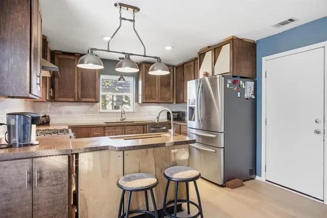 a kitchen with stainless steel appliances granite countertop a refrigerator a sink a stove and island