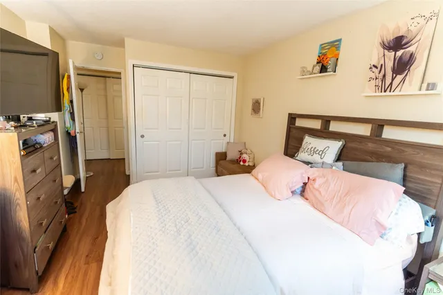 a bedroom with a bed a flat screen tv and a window