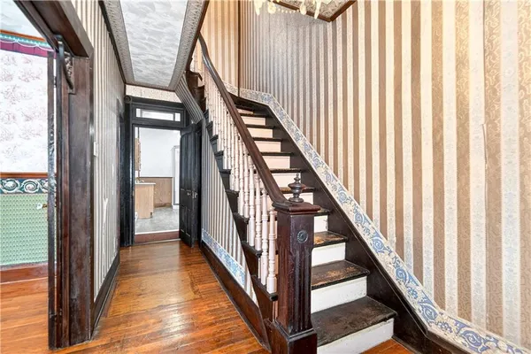 a view of staircase with lots of frames on wall and wooden floor