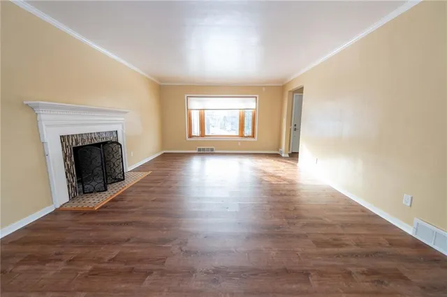 an empty room with wooden floor fireplace and windows