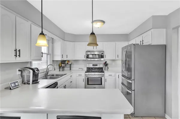 a kitchen with stainless steel appliances a stove a sink a refrigerator cabinets and a window