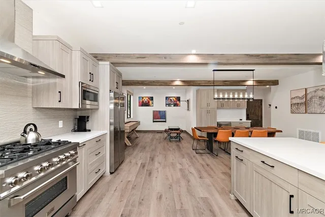 a large kitchen with stainless steel appliances granite countertop a lot of counter space and wooden floors