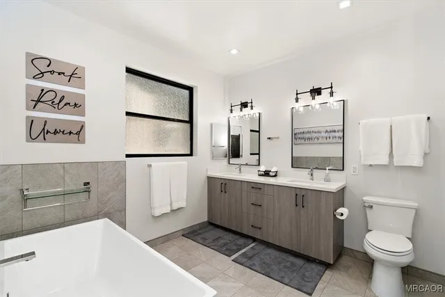 a bathroom with a double vanity sink toilet and mirror