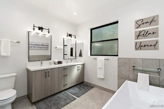a spacious bathroom with a double vanity sink toilet and mirror
