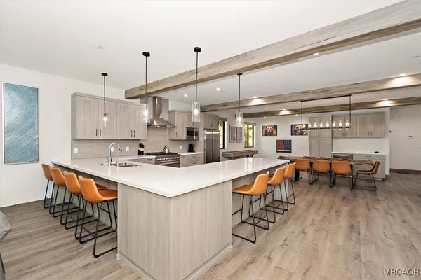a kitchen with stainless steel appliances a table chairs in it and wooden floors