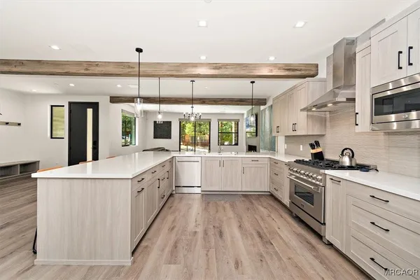 a large kitchen with stainless steel appliances a lot of counter top space and wooden floor