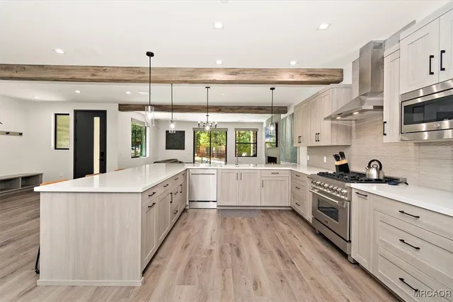 a large kitchen with stainless steel appliances a lot of counter top space and wooden floor