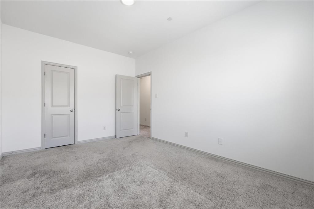 6141 Roper Road McKinney, TX 75070 - Photo 29 of 35 Neutral-toned room featuring a light gray carpet, white walls, and two paneled doors with gray trim