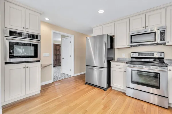 a kitchen with wooden floors and white cabinets