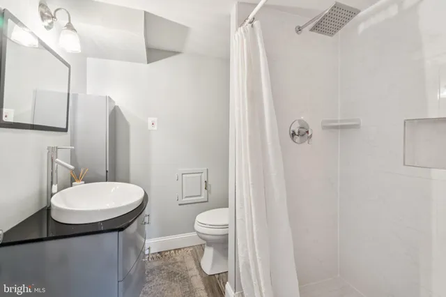 a bathroom with a sink a toilet a mirror and shower