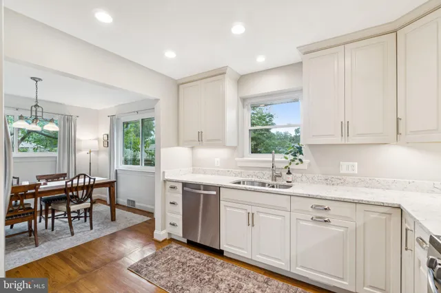 a kitchen with a sink white cabinets and glass table chairs