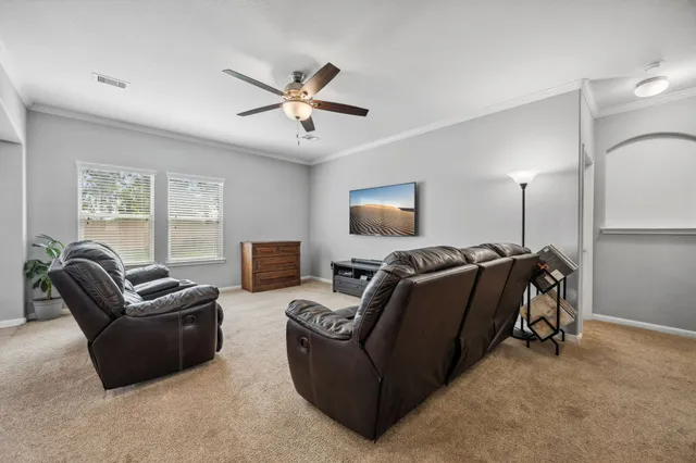 a living room with furniture a ceiling fan and a flat screen tv
