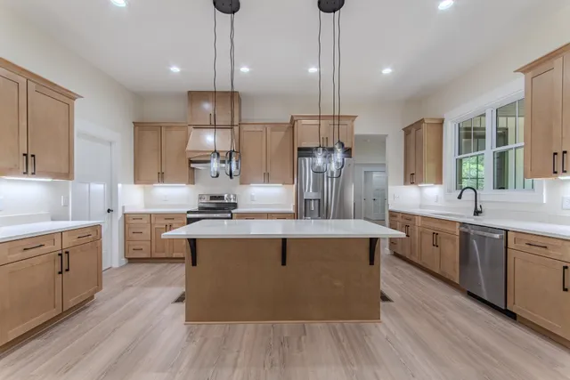 a kitchen with stainless steel appliances granite countertop a sink a stove and a wooden floors