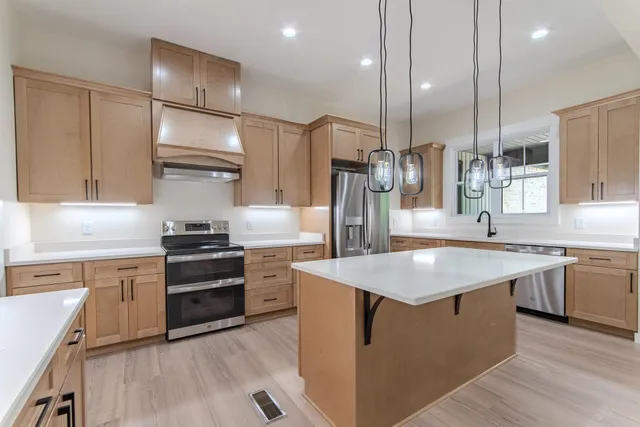 a kitchen with stainless steel appliances granite countertop a sink a stove and a refrigerator