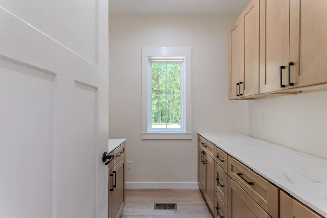 a view of a kitchen with white cabinets and a window
