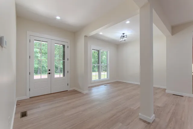 an empty room with wooden floor and windows