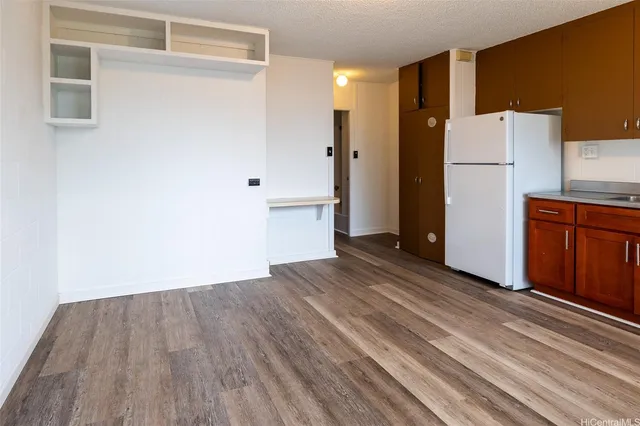 a view of a kitchen with wooden floor and a refrigerator