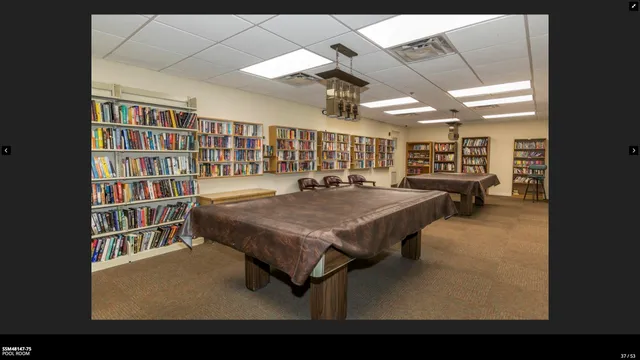 a view of swimming pool with lawn chairs and plants