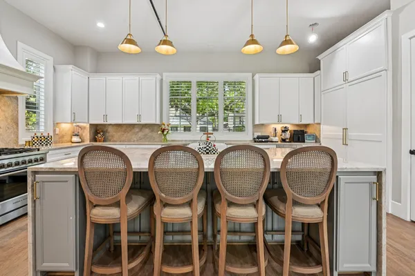 a kitchen with granite countertop a table chairs stove and microwave