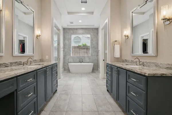 a spacious bathroom with a granite countertop double vanity sink a mirror and a bathtub