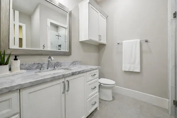 a bathroom with a granite countertop toilet sink and mirror