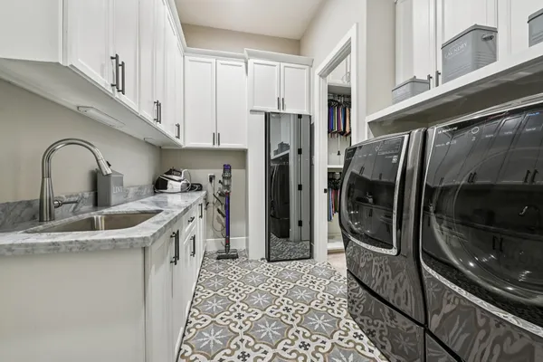 a kitchen with stainless steel appliances granite countertop a sink a stove a washer and dryer