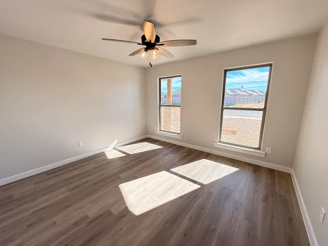 a view of empty room with wooden floor and fan