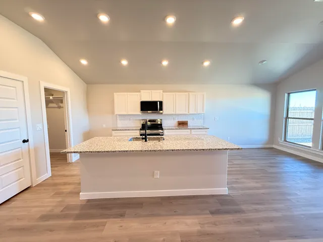 a view of kitchen with stainless steel appliances granite countertop refrigerator stove sink and cabinets