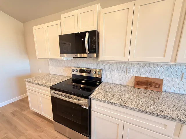 a kitchen with stainless steel appliances granite countertop white cabinets and a stove