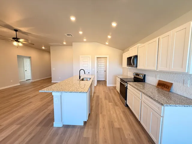 a large kitchen with stainless steel appliances granite countertop a lot of counter space and wooden floor