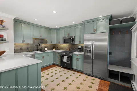 a kitchen with stainless steel appliances kitchen island granite countertop a sink refrigerator and cabinets