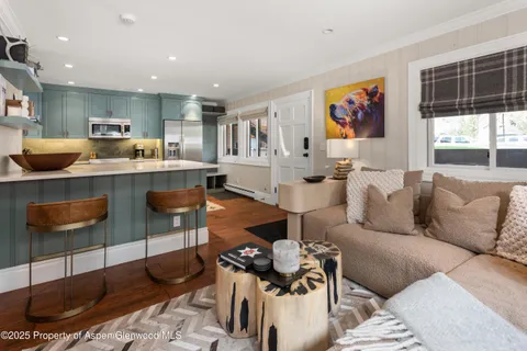 a living room with furniture kitchen view and a window