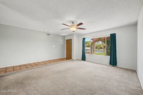 an empty room with windows and chandelier fan