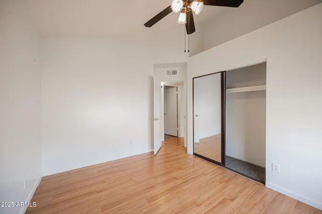 an empty room with wooden floor fan and windows