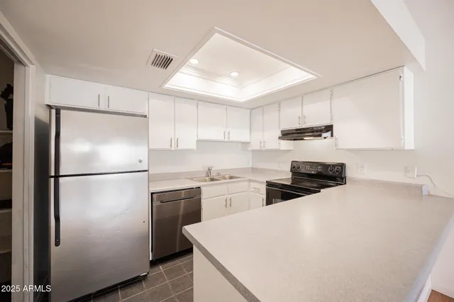 a kitchen with refrigerator a stove a sink and white cabinets