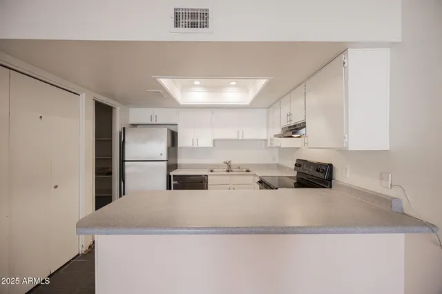 a kitchen with kitchen island a sink a refrigerator and white cabinets