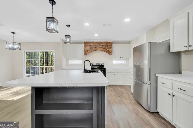 a kitchen with kitchen island a counter top space a sink a refrigerator and wooden floor