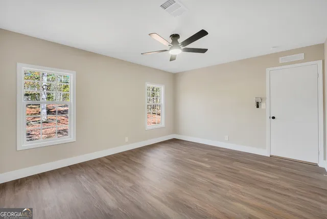 a view of an empty room with wooden floor and a window