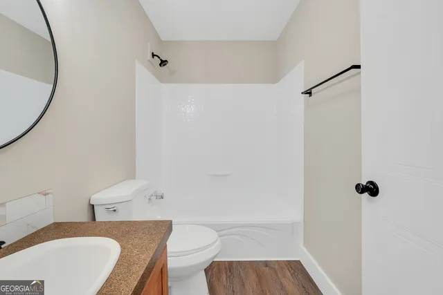 a white toilet sitting next to a bathroom sink and a mirror