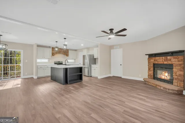 a view of an empty room with a kitchen and a window