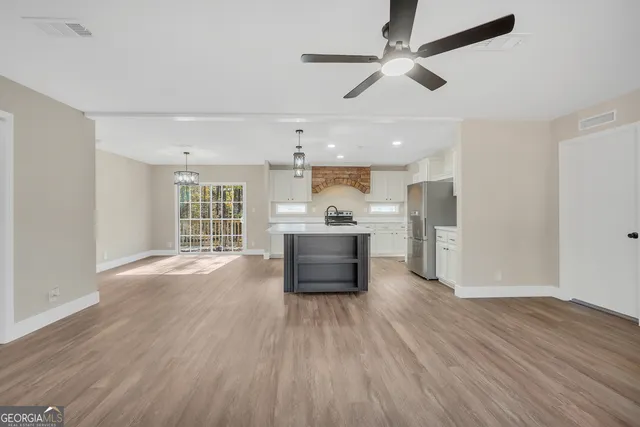 a living room with stainless steel appliances kitchen island hardwood floor and a window