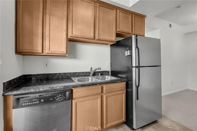 a kitchen with stainless steel appliances granite countertop a refrigerator a stove a sink and dishwasher