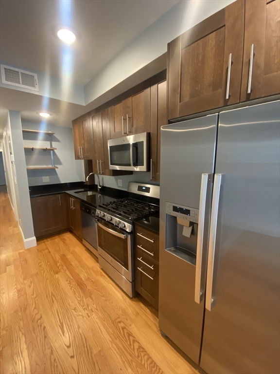 186 Kelton Street, Unit 2 Boston, MA 02134 - Photo 2 of 11 a kitchen with stainless steel appliances granite countertop a refrigerator a stove and a sink