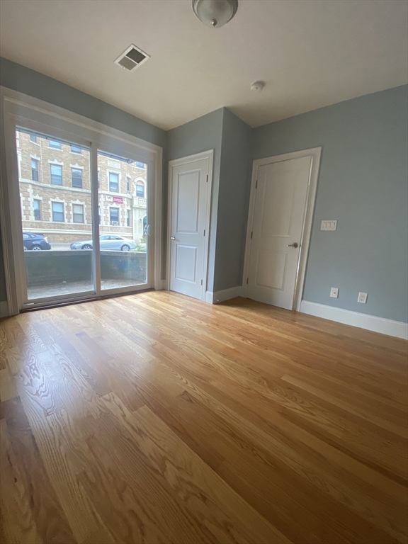 186 Kelton Street, Unit 2 Boston, MA 02134 - Photo 5 of 11 a view of an empty room with wooden floor and a window